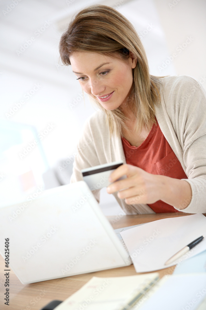 Cheerful middle-aged woman buying on internet Cheerful middle-aged woman buying on internet