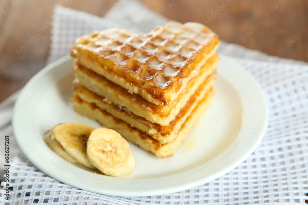 Sweet Belgium waffles with banana, on wooden table background Sweet Belgium waffles with banana, on wooden table background