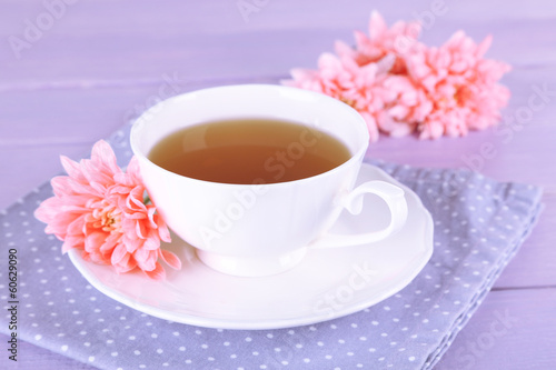 Pink chrysanthemums and cup of tea on wooden table