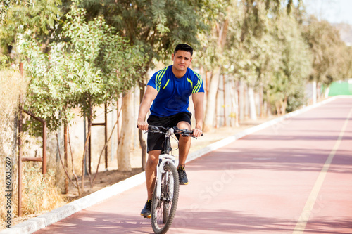 Fototapeta Naklejka Na Ścianę i Meble -  Young Latin man riding a bike