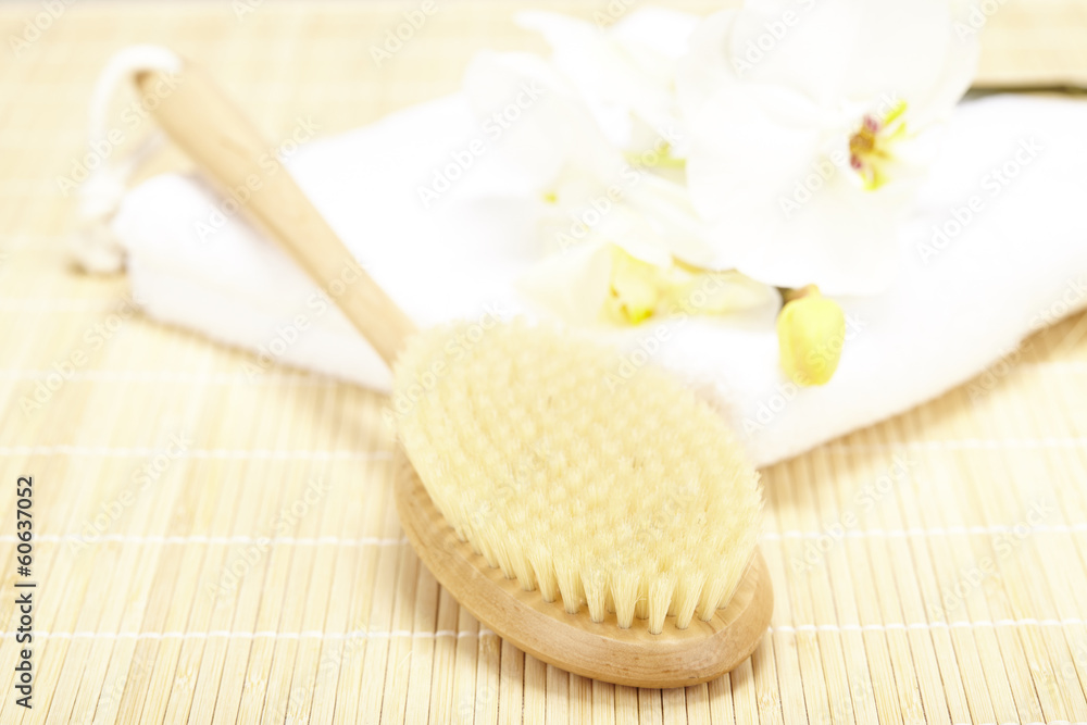 Handtuck, Badebürste und Orchidee auf Bambusmatte Handtuck, Badebürste und Orchidee auf Bambusmatte