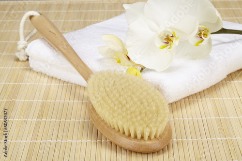 Handtuck, Badebürste und Orchidee auf Bambusmatte