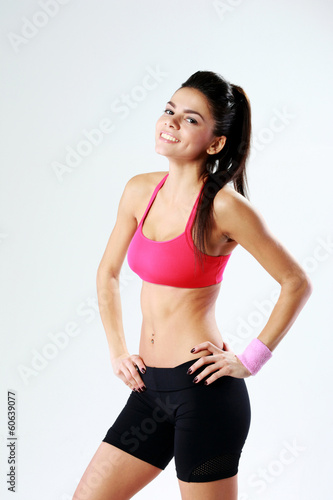 Young smiling sport woman standing on gray background