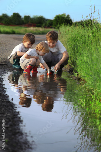 three boy play in  puddle