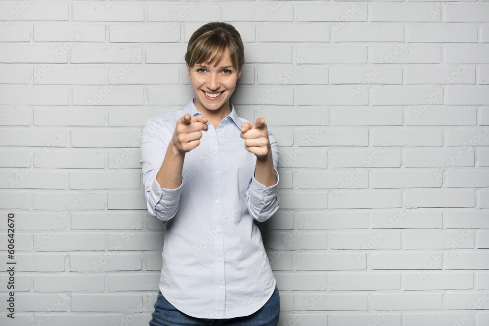 Smiling Cute woman pointing a fingers isolated over the wall Smiling Cute woman pointing a fingers isolated over the wall
