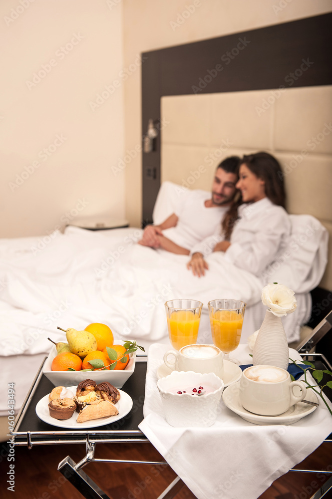 Young happy couple having breakfast in luxury hotel room.