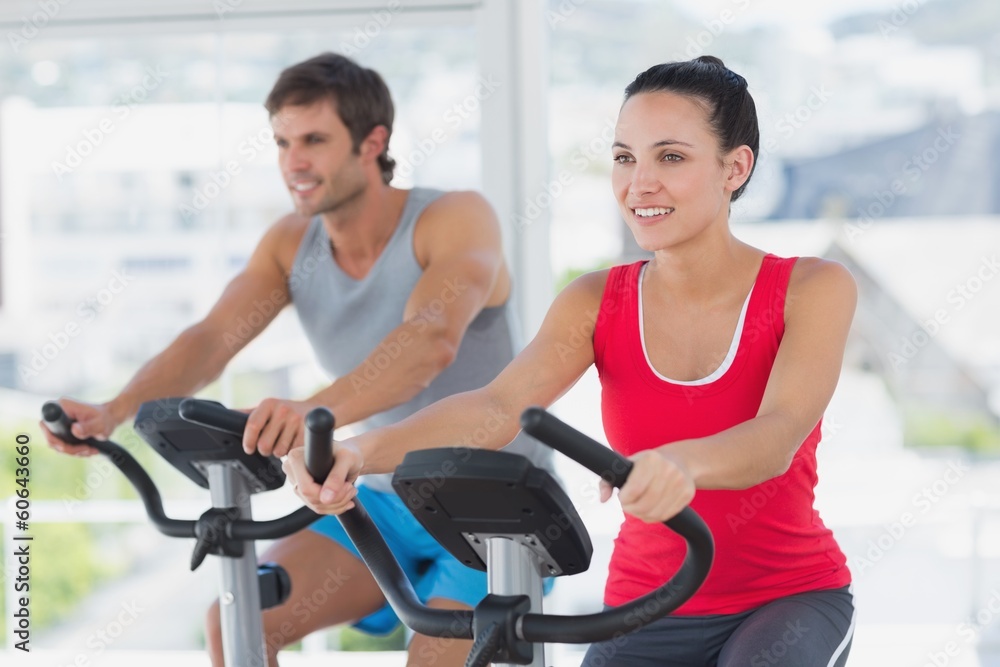 Smiling young couple working out at spinning class Smiling young couple working out at spinning class