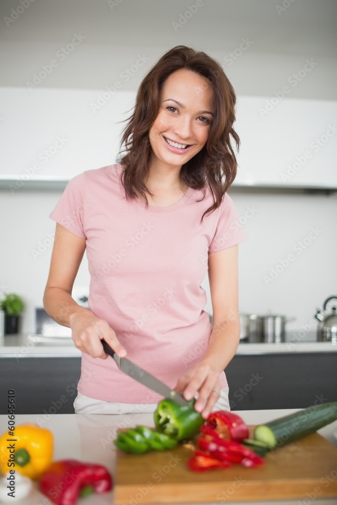 Smiling young woman chopping vegetables in kitchen Smiling young woman chopping vegetables in kitchen