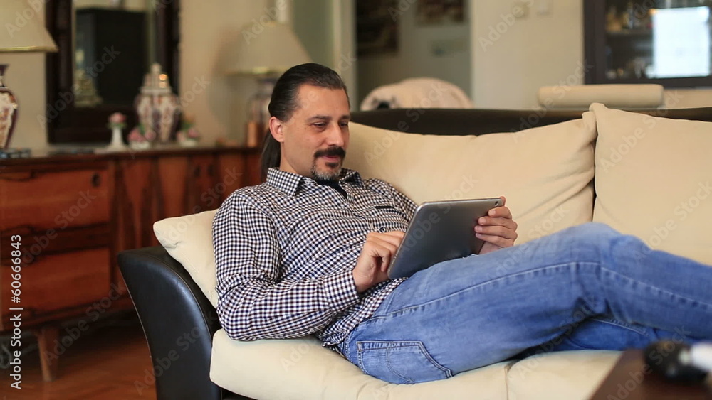 attractive handsome lieying sofa and using tablet attractive handsome lieying sofa and using tablet