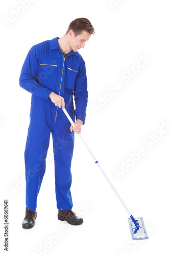 Worker In Boilersuit Cleaning Floor