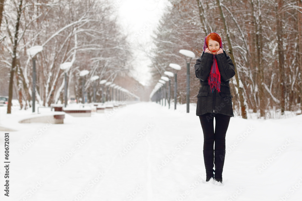 Beautiful girl in black stands outdoor at winter day in park