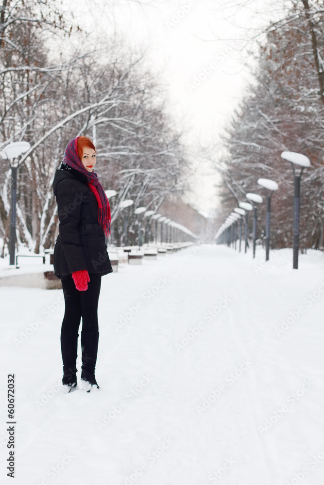 Beautiful girl in black stands and smiles outdoor at winter day