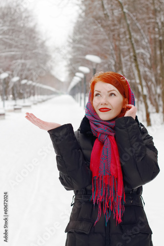 Pretty happy girl in red kerchief catches snowflakes outdoor