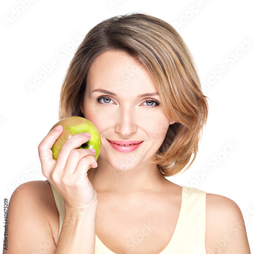 Young beautiful smiling woman touches the apple to face.