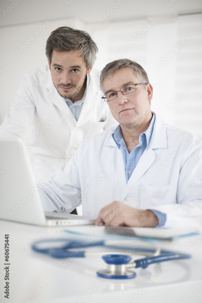 Clinical Director and his assistant discussing around a computer Clinical Director and his assistant discussing around a computer