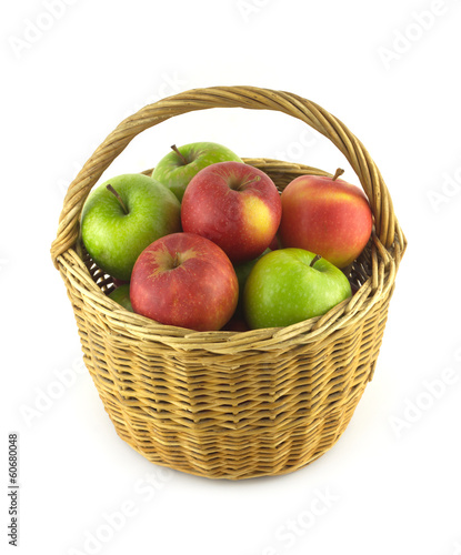 Ripe green and red apples in brown wicker basket isolated