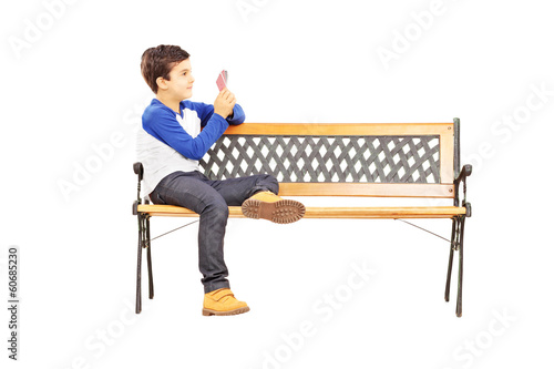 Fotografie Boy seated on bench and playing cards with imaginary friend