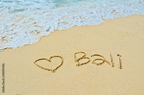 Bali title with sun and palm drawing on the sand beach near the