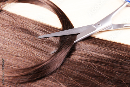 Long brown hair and scissors on wooden background