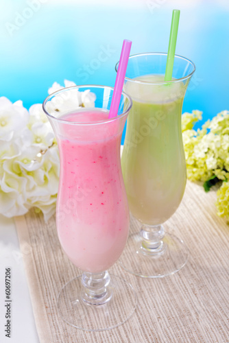 Milk shakes on table on light blue background