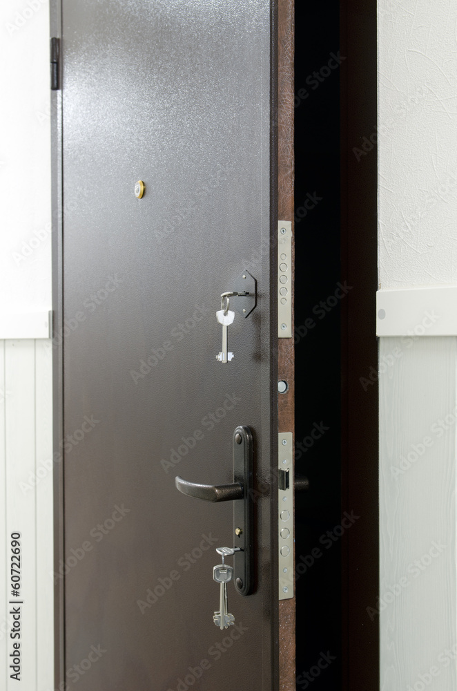 Opened metal door with keys in keyhole Opened metal door with keys in keyhole