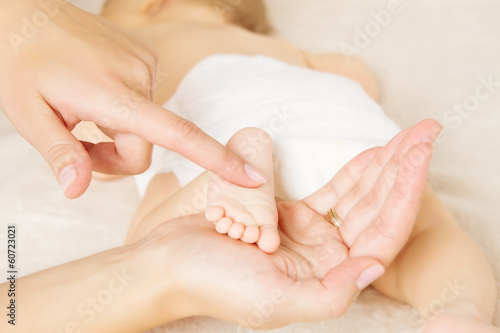 Masage newborn baby foot in mother hand