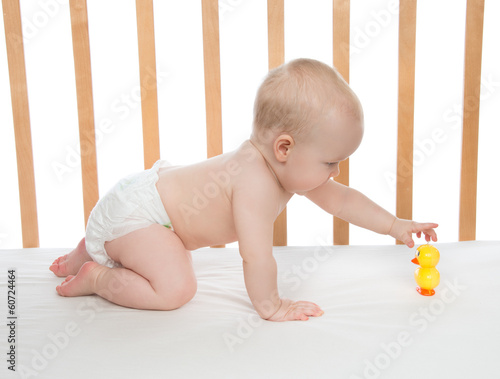 little child baby girl crawling in bed with toy duck