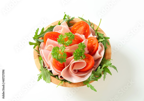 Sliced ham with arugula and tomatoes