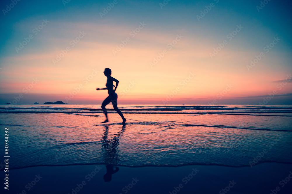 Silhouette of a woman jogger on the beach at sunset