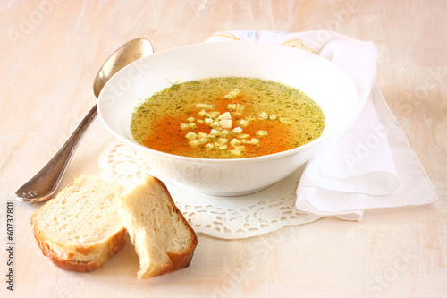 chicken soup with carrots over white wooden textured background