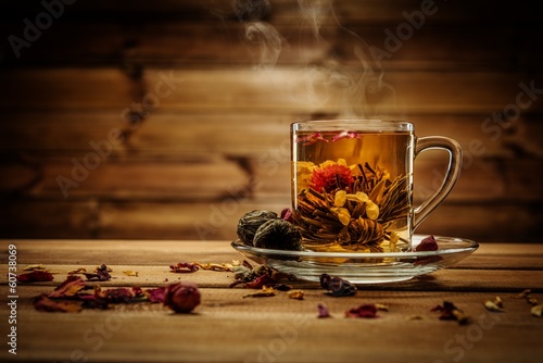 Glass cup with tea flower against wooden background