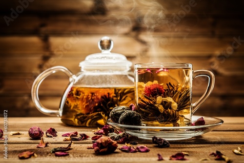 Teapot and glass cup with blooming tea flower inside