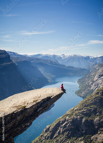 man sitting on trolltunga rock in norway