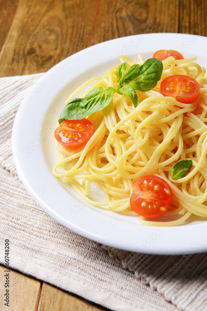 Delicious spaghetti with tomatoes on plate on table close-up Delicious spaghetti with tomatoes on plate on table close-up