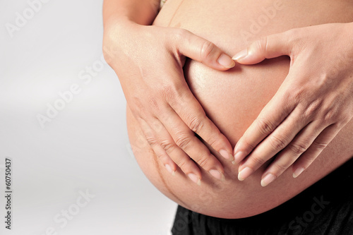 Pregnant Woman holding her hands in a heart shape on her baby