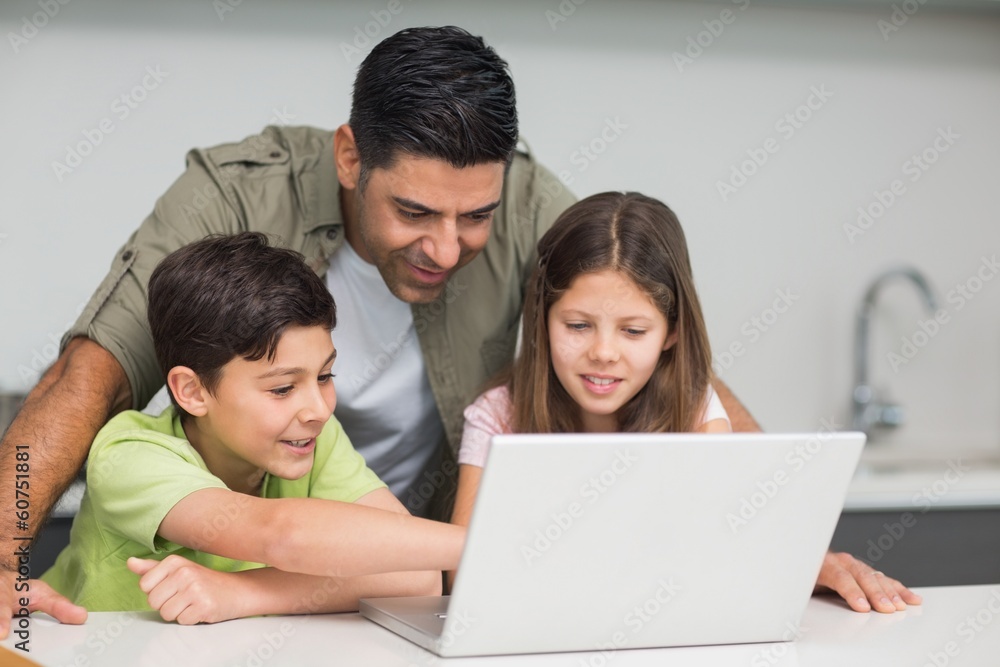 Father with young kids using laptop in kitchen Father with young kids using laptop in kitchen