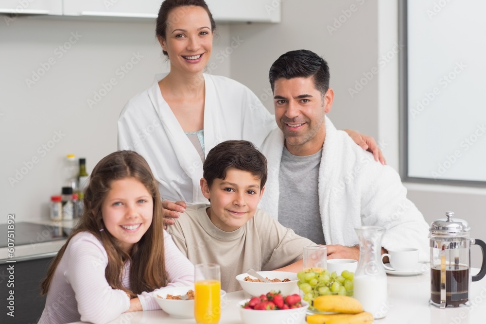 Portrait of happy kids enjoying breakfast with parents