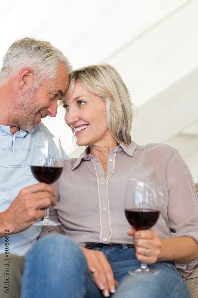 Smiling mature couple with wine glasses sitting on sofa Smiling mature couple with wine glasses sitting on sofa