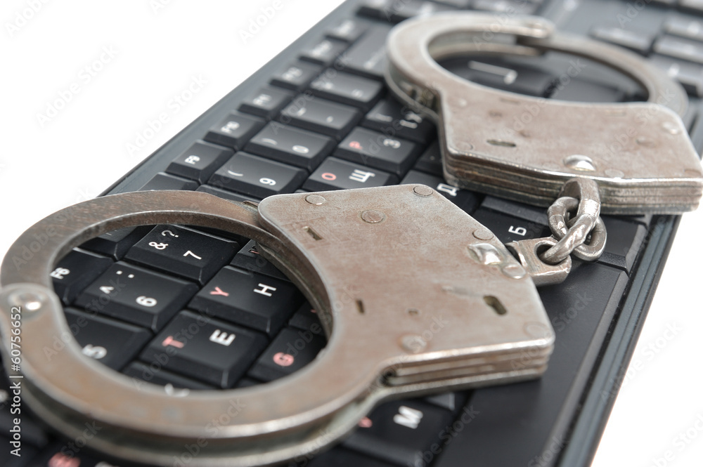 Fototapeta premium Handcuffs on the keyboard on white background