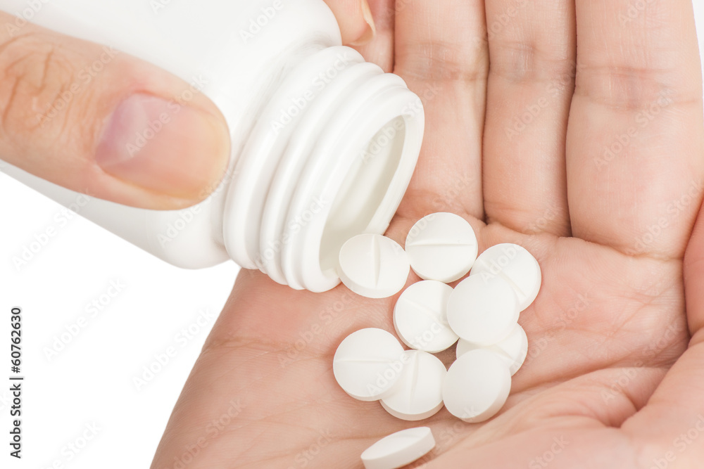 Closeup of medicine capsules being poured from pill bottle into Closeup of medicine capsules being poured from pill bottle into