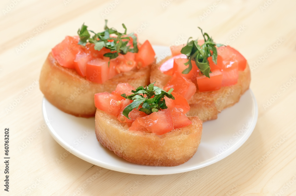 Toasted bread with tomatoes on white plate Toasted bread with tomatoes on white plate