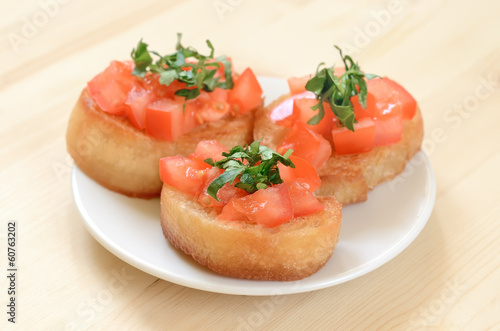 Toasted bread with tomatoes on white plate