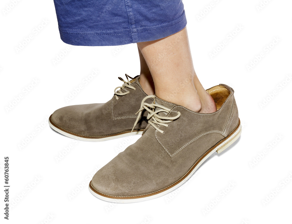 The little boy tried on the boots of the adult The little boy tried on the boots of the adult
