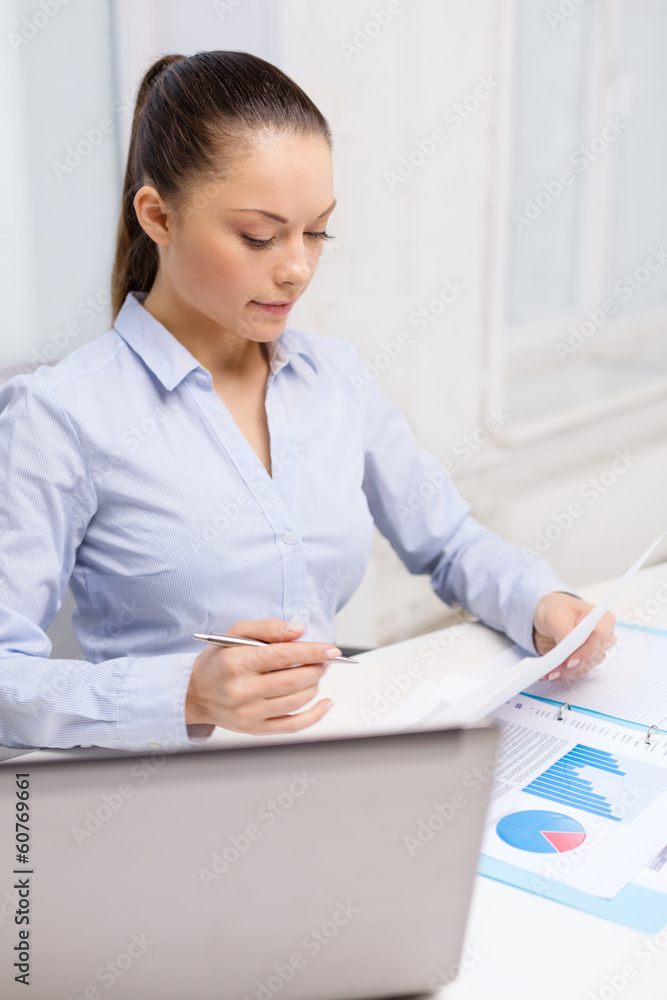 businesswoman with laptop and charts in office businesswoman with laptop and charts in office