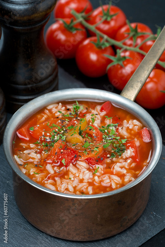 Spicy tomato soup with rice, vegetables and herbs in a saucepan