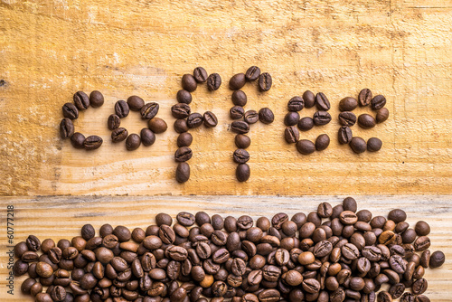 Light wood background texture with coffee beans writing the word "coffee"