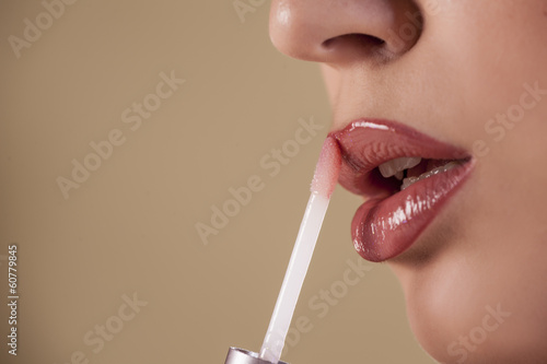 Woman applying lip gloss photo