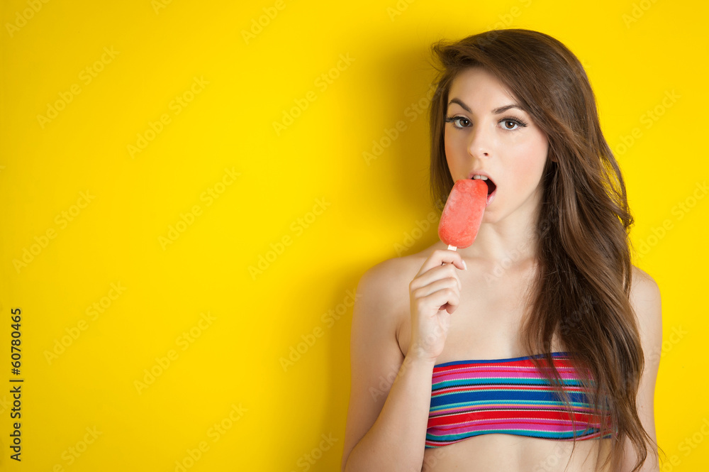 Beautiful girl eating a ice cream against yellow background with Beautiful girl eating a ice cream against yellow background with