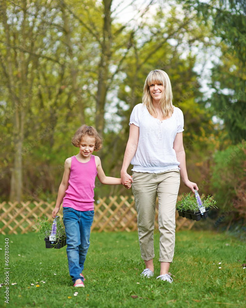 Fototapeta premium Frau und Kind mit Pflanzen im Garten