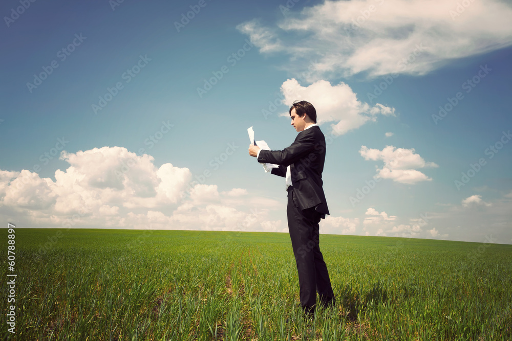 businessman standing on a field with a blue sky and reads the ne businessman standing on a field with a blue sky and reads the ne